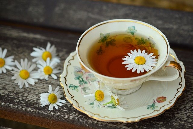 eine Teetasse mit einer Kamillenblüte drin 