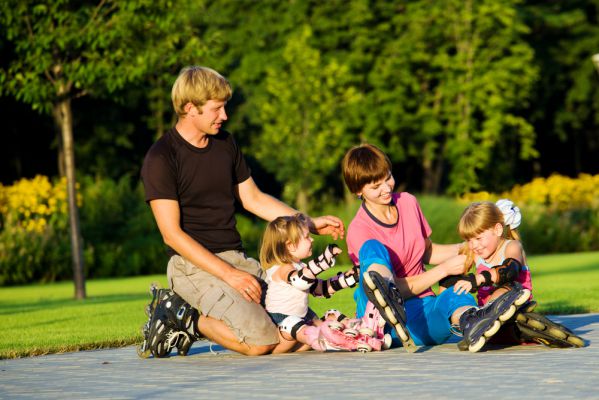Eine Familie sitzt im Park un sieht Inline-Skates an. 