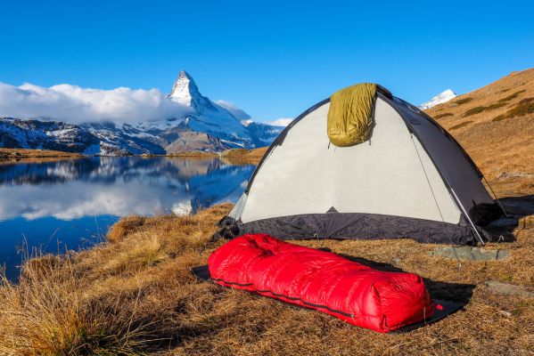 ein Schlafsack und Zelt in der Nähe eines Bergsees