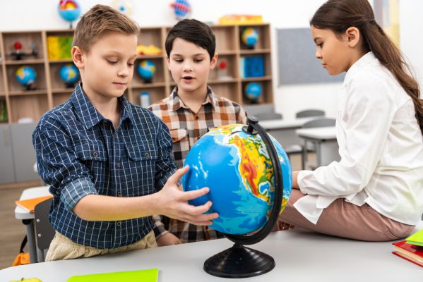 drei Kinder sehen sich einen Globus an