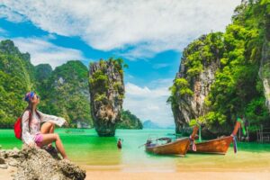 Urlauberin sitzt am Strand in Thailand und genießt die Aussicht.