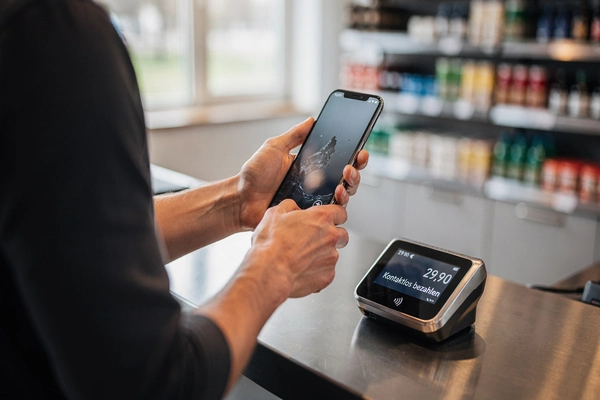 ein Mann hat ein Smartphone in der Hand und möchte damit kontaktlos bezahlen