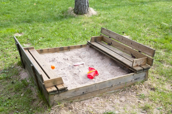 ein Sandkasten mit einem roten Eimer drin